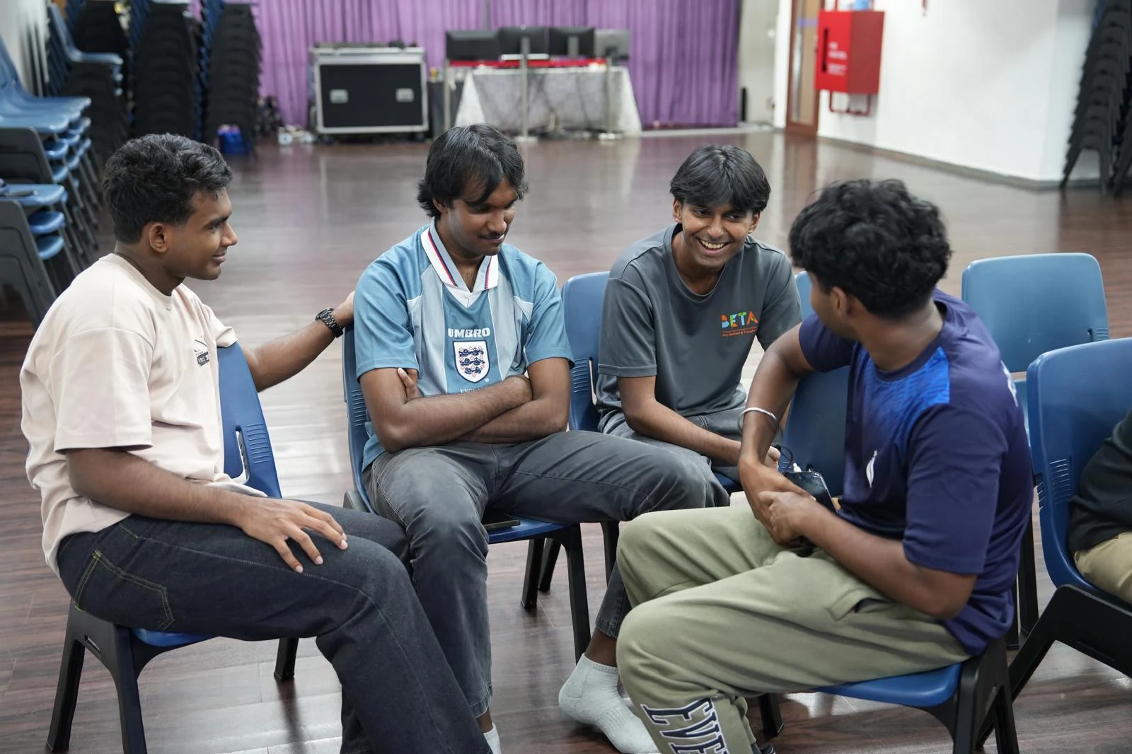 Four young people seated in a circle, talking together