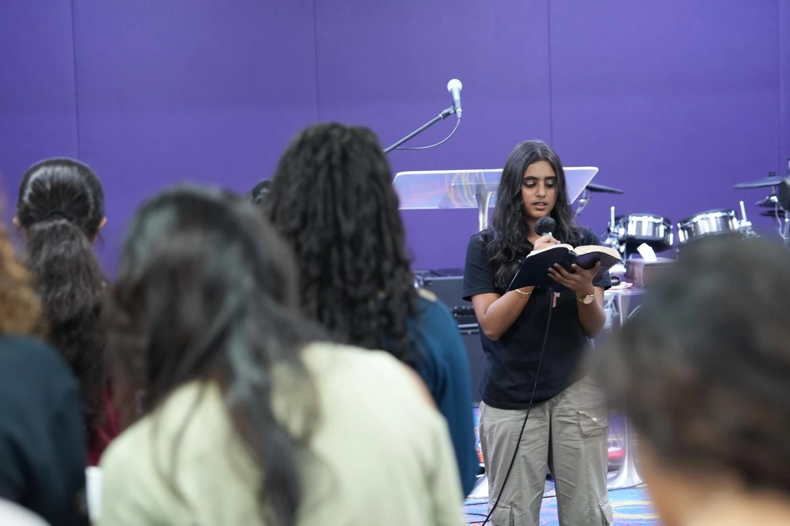 A person reading from an open book as others listen